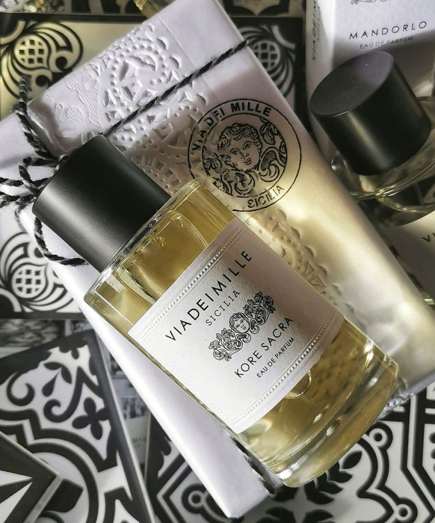 Perfume Via Dei Mille Kore Sacra Eau de Parfum 100 ml con frasco sobre fondo decorativo en blanco y negro